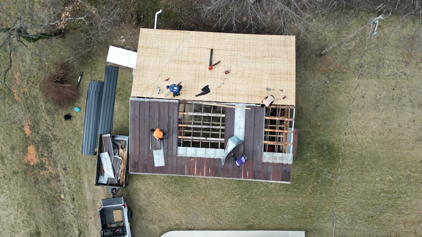 Aerial view of a RuFR USA crew re-roofing a commercial building in Western North Carolina, decking exposed and new roofing going on