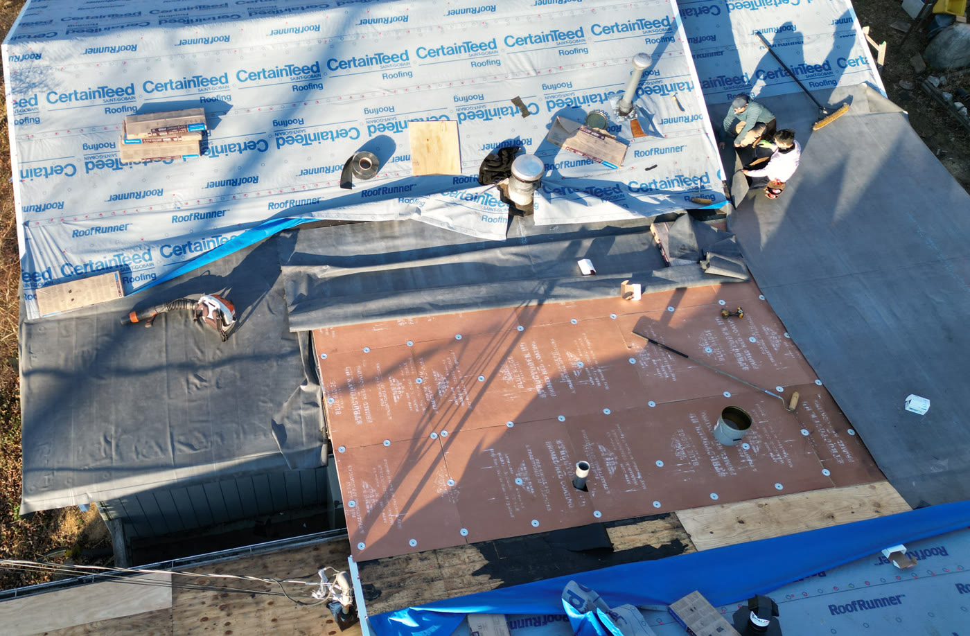 Aerial view of a RuFR USA low-slope roof mid-install, with CertainTeed synthetic underlayment and ice-and-water shield layered across the shallow-pitch planes