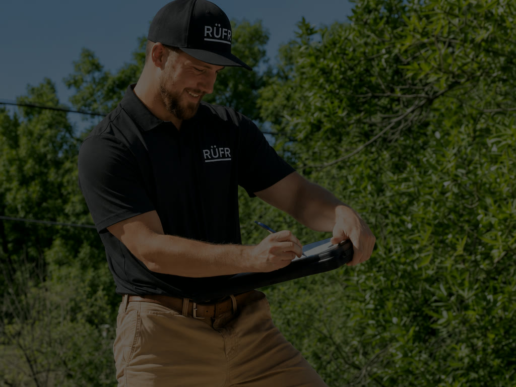 A RuFR USA inspector in a branded polo documenting a roof inspection on a Western North Carolina home