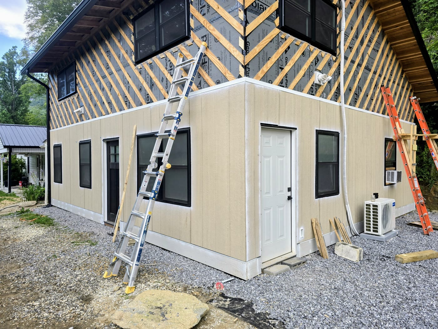 A RuFR USA siding installation in progress on a Western North Carolina home, with housewrap on the upper wall and finished panels below