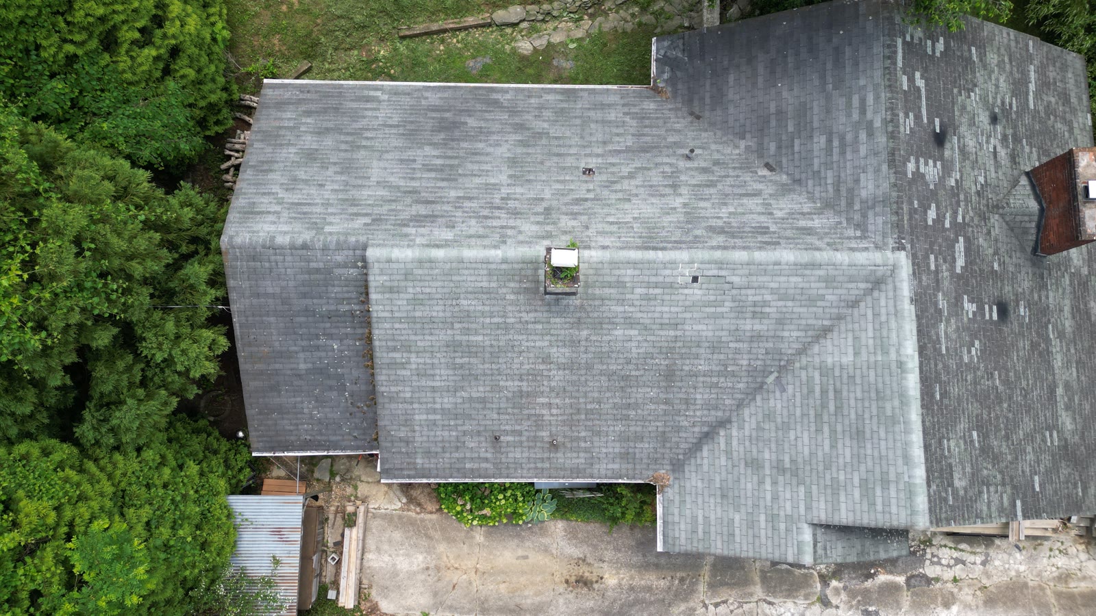 Aerial drone view of a weathered asphalt shingle roof on a Western North Carolina home showing wind wear and damage across the slopes
