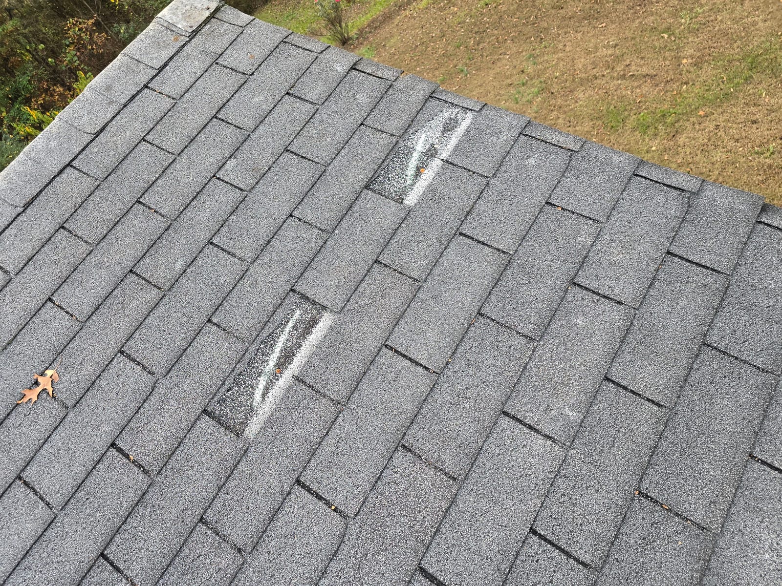 Wind-lifted asphalt shingles with broken adhesive seals on an Asheville, NC roof