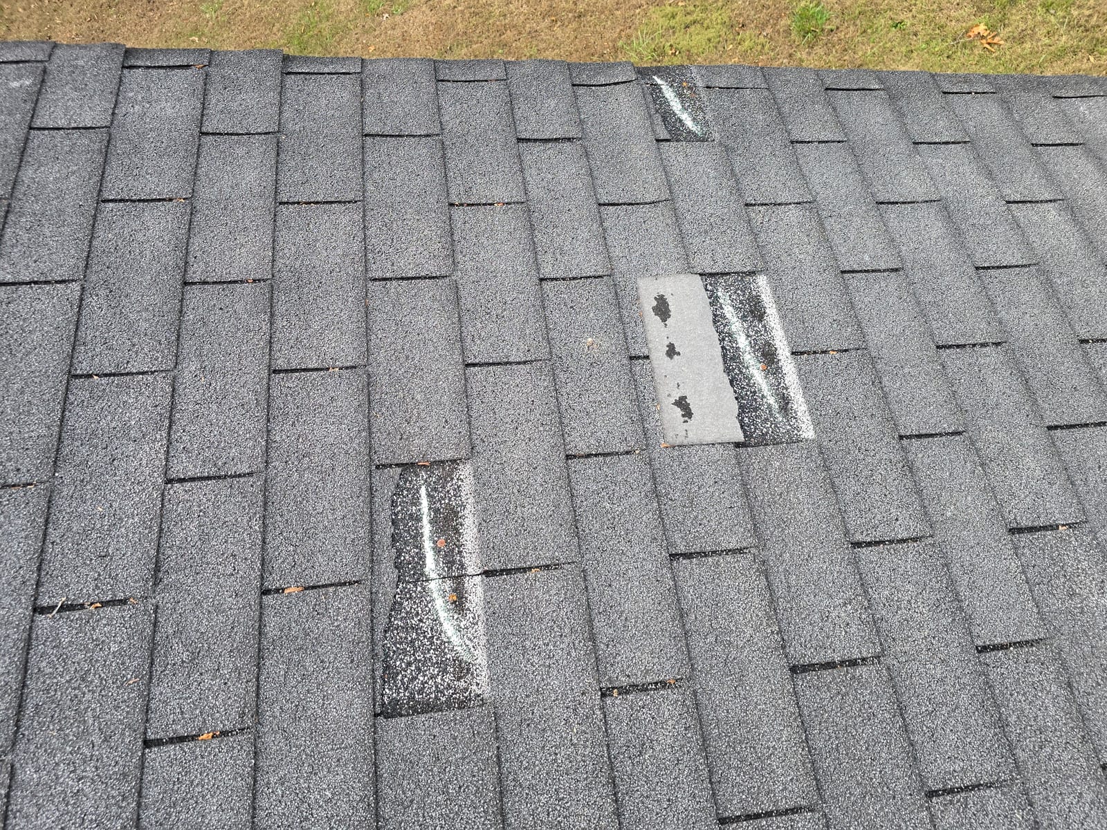 A torn shingle tab and granule loss from wind on an Asheville, NC roof