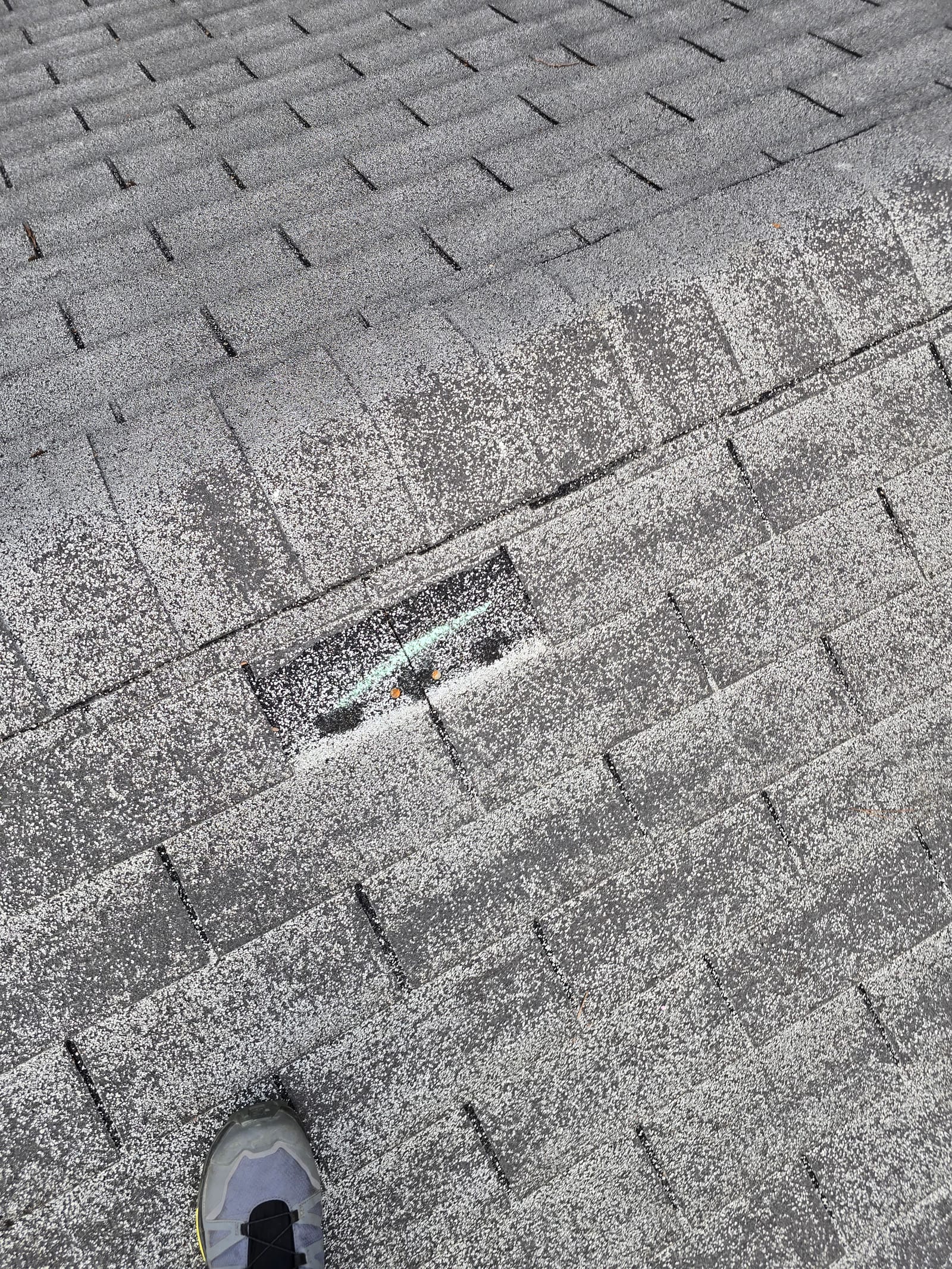 A wind-lifted shingle exposing nail heads, marked during a roof inspection in Asheville, NC